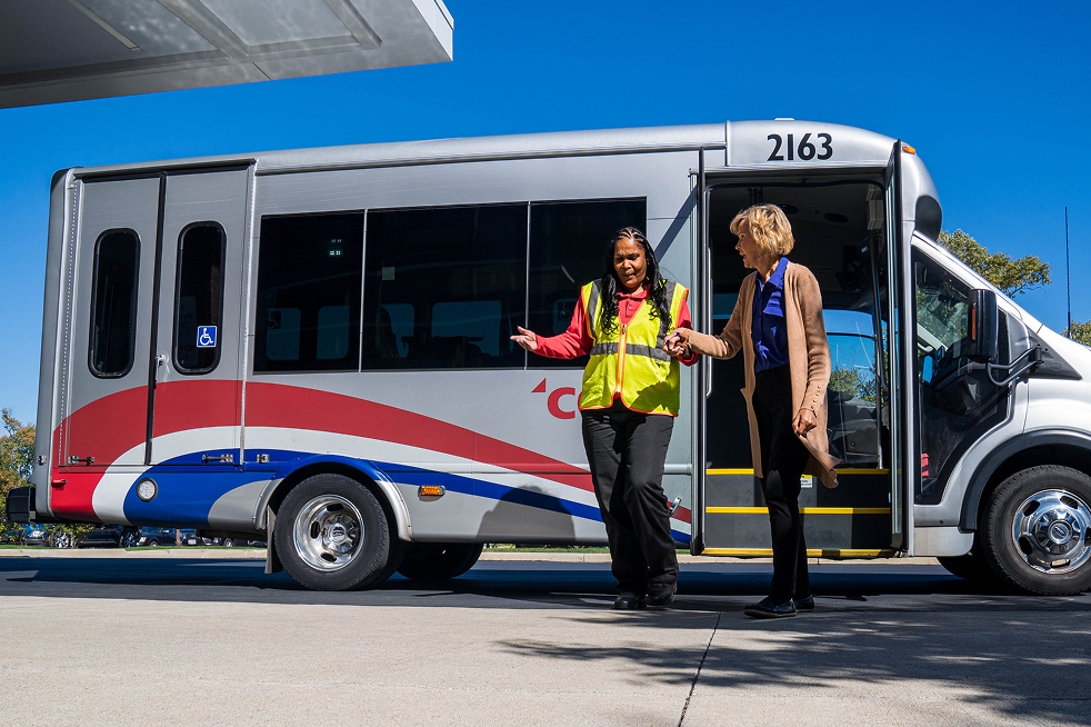 A COTA employee assisting a passenger from a COTA Mainstream vehicle